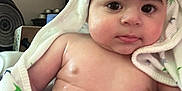Michael is registered to the contest to win money with this photo: baby, child, towel, wet_hair, indoors, face, skin, arm, chubby, expression, cute, newborn, portrait, person, infant, closeup, soft, blanket, wrapped, curious