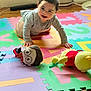 Michael is registered to the contest to win money with this photo: baby, child, crawling, indoor, foam_mat, colorful, plush_toys, toy, floor, happy, smiling, person, young_child, clothing, face, wooden_floor, playtime, cute, home, bright