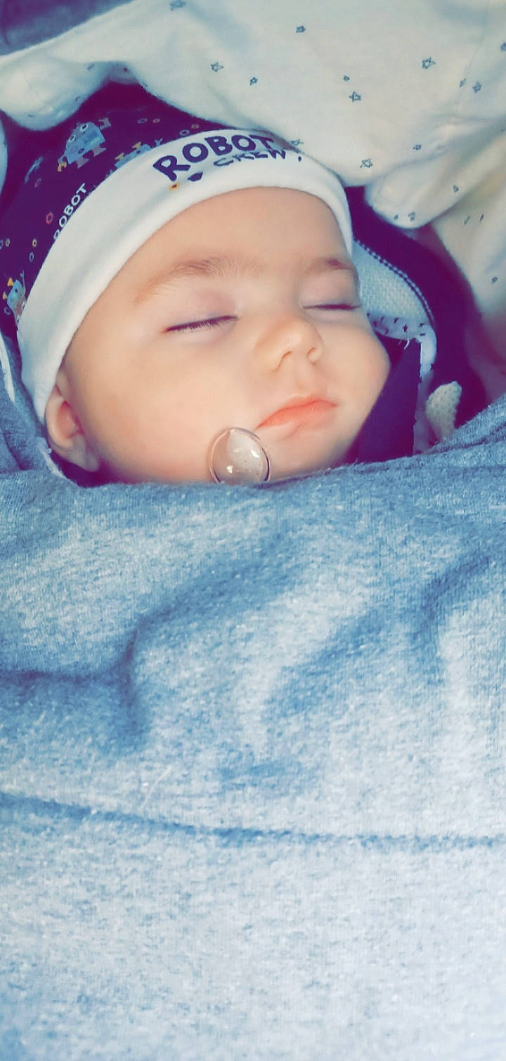 Killian participe au concours pour gagner de l'argent avec cette photo : azure, baby, baby_products, baby_sleeping, baby_toddler_clothing, beanie, blue, cap, cheek, child, comfort, electric_blue, happy, headwear, knit_cap, linens, person, portrait_photography, skin, toddler