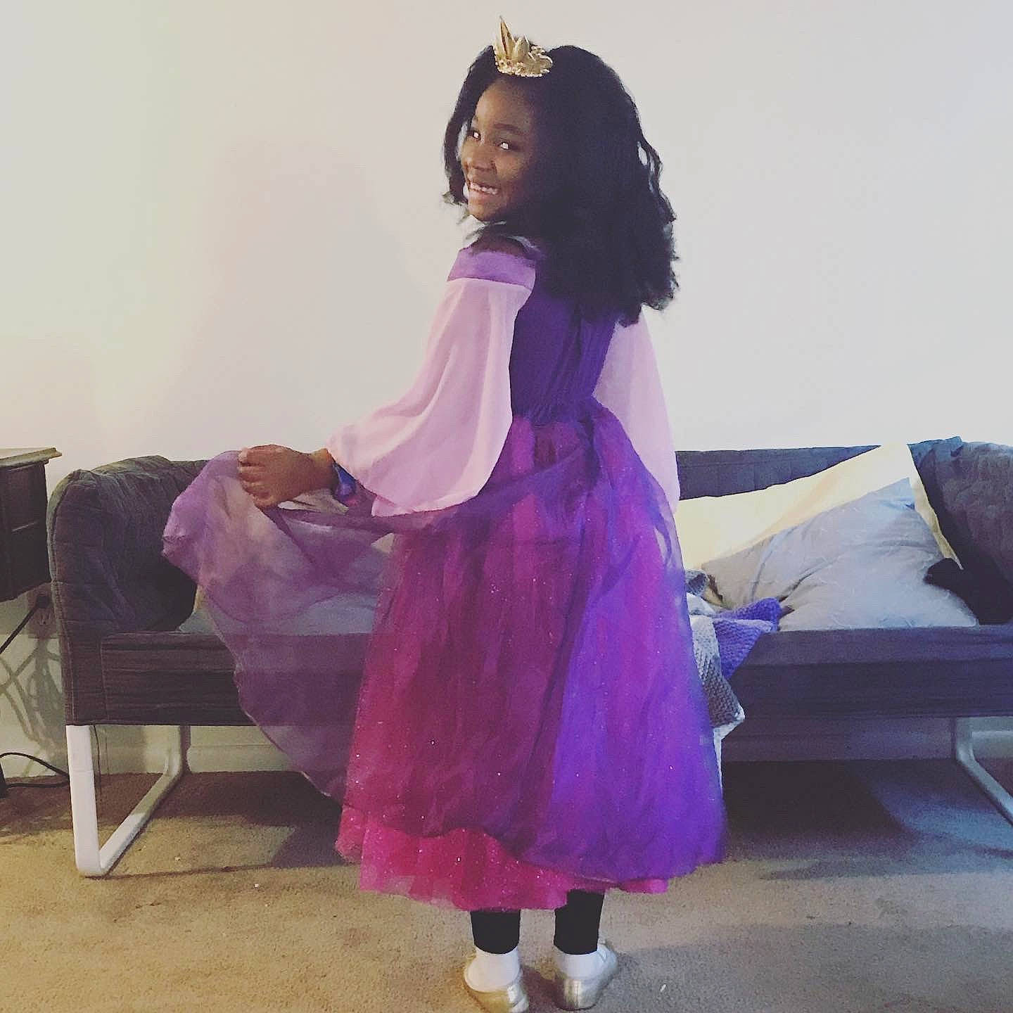 Kyrah is registered to the contest to win money with this photo: child, comfort, costume, couch, day_dress, event, fashion_accessory, fashion_design, fashion_model, formal_wear, fun, hair, happy, joy, long_hair, magenta, person, purple, sitting, sleeve