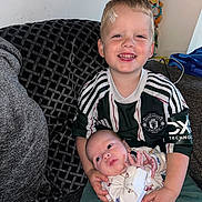 Cameron is registered to the contest to win money with this photo: child, baby, smile, couch, indoor, clothing, boy, sitting, happy, face, infant, pattern, toy, home, person, casual, manchester_united, holding, cute, family