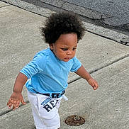 Ravi joined the competition — help win amazing prizes! child, toddler, walking, outdoor, sidewalk, street, portrait, blue_shirt, white_shorts, curly_hair, afro_hair, concentrated, determined, standing, movement, pavement, urban, daylight, clothing, manhole_cover