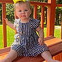 toddler, child, yellow_bow, outdoor, bench, wooden_bench, dress, checkered_dress, greenery, sunlight, summer, portrait, baby, cute, sitting, smiling, nature, daylight, park, happy