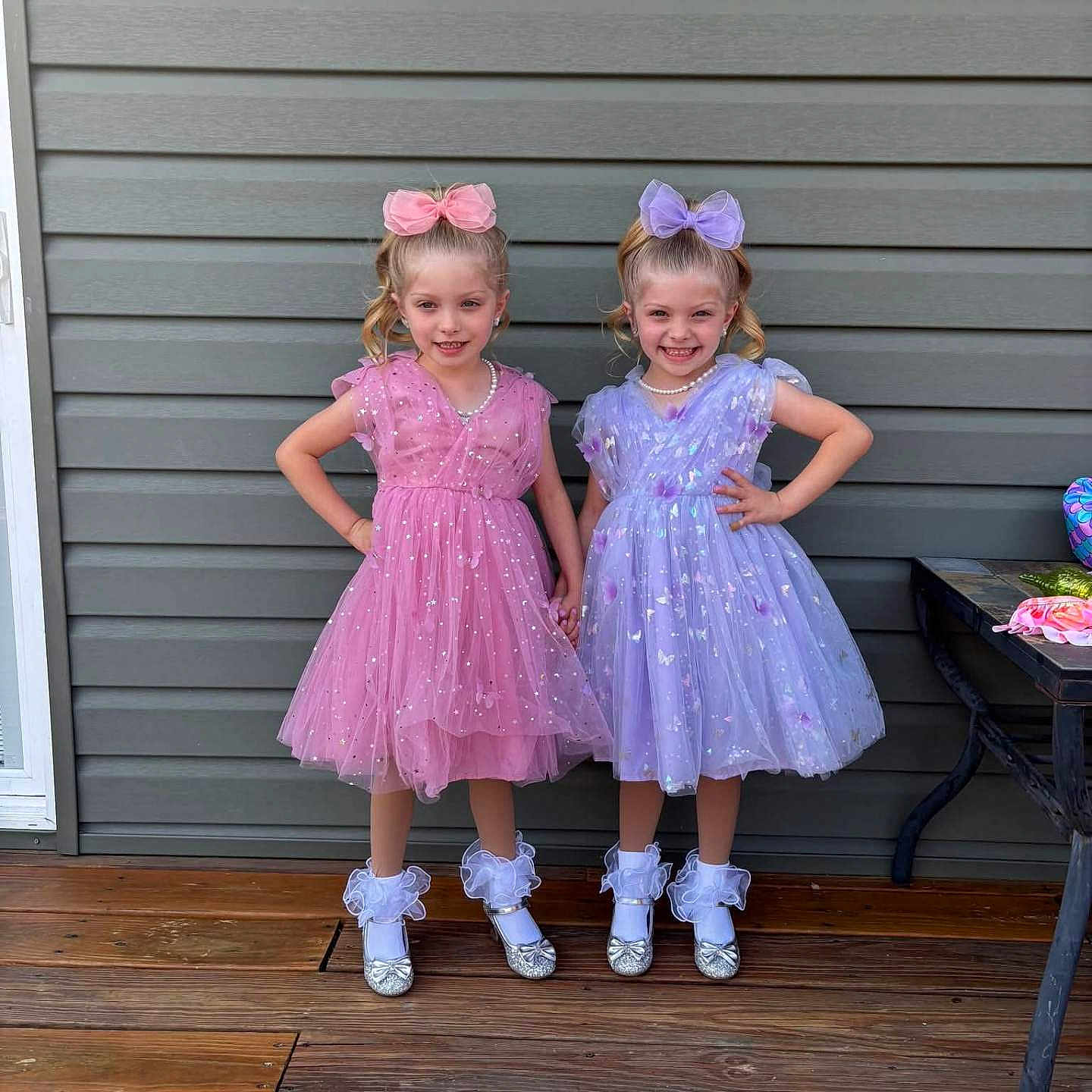 Avalinaandandilyn is registered to the contest to win money with this photo: bow, child, children, dress, fashion, girl, hair_bow, happy, holding_hands, outdoor, pearls, pink_dress, pose, purple_dress, shoes, smile, socks, twins, wall, wooden_deck