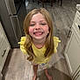 Avalinaandandilyn is registered to the contest to win money with this photo: child, girl, smiling, blonde_hair, barefoot, yellow_shirt, kitchen, wooden_floor, cabinet, refrigerator, happy, standing, indoor, person, face, long_hair, casual_clothing, home, bright, portrait
