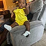 toddler, child, yellow_outfit, sock, couch, living_room, carpet, adult_hand, curtain, furniture, person, home_interior, playful, smiling, indoors, support, window, seat, baby, expression