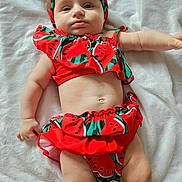 Olivia joined the competition — help win amazing prizes! baby, blanket, child, chubby, closeup, cute, expression, fashion, headband, indoors, infant, lying_down, one_person, playful, red_clothing, skin, soft_texture, summer_outfit, toddler, watermelon