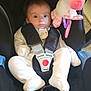 baby, infant, car_seat, unicorn_toy, plush_toy, white_clothing, straps, pacifier, indoors, car_seat_harness, child, cute, soft_toy, seat, child_safety, young_baby, car_seat_padding, floor, car_seat_buckle, toy