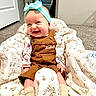 baby, child, smile, headband, overalls, quilt, carpet, indoor, happy, seated, person, clothing, footwear, pattern, fabric, cute, infant, joy, home, cozy