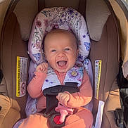 Lainey is registered to the contest to win money with this photo: baby, car_seat, smile, infant, child, pink_clothing, floral_pattern, sunlight, happy, cute, seat_belt, safety, outdoor, infant_clothing, portrait, baby_girl, carriage, padding, baby_accessory, baby_toy