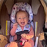 baby, car_seat, smile, infant, child, pink_clothing, floral_pattern, sunlight, happy, cute, seat_belt, safety, outdoor, infant_clothing, portrait, baby_girl, carriage, padding, baby_accessory, baby_toy