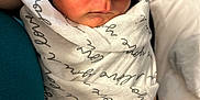 Luca is registered to the contest to win money with this photo: newborn, baby, sleeping, swaddle, beanie, nike, hat, infant, peaceful, resting, closeup, portrait, cozy, fabric, textile, human, child, soft_light, indoor, person