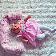 Ciarah Aaliyah is registered to the contest to win money with this photo: baby, infant, pink_dress, headband, white_tights, lying_down, blanket, plush, soft_texture, cute, child, smiling, indoors, cozy, portrait, adorable, resting, happy, baby_clothing, toddler