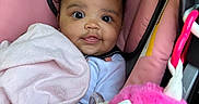 Dazaiah joined the competition — help win amazing prizes! baby, car_seat, child, clothing, curly_hair, cute, face, hand, happy, head, indoors, infant, person, pink_blanket, plush_toy, portrait, seatbelt, smiling, soft_toy, warning_label