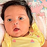 baby, infant, face, eyes, hair, yellow_clothing, watermelon_pattern, blanket, unicorn, pink_background, cute, portrait, child, lying_down, soft_bedding, indoors, skin, expression, mouth_open, newborn
