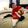Aron joined the competition — help win amazing prizes! bed, bedroom, black_pants, blanket, casual, child, curtains, framed_pictures, happy, headboard, indoor, person, plush_doll, red_sweater, sitting, smiling, socks, toy, white_shoes, window