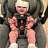 Serenity joined the competition — help win amazing prizes! baby, infant, child, smiling, helmet, protective_headgear, car_seat, harness, safety, pink_clothing, knitwear, fluffy_socks, seated, portrait, indoor, wooden_floor, happy, face, vehicle_equipment, adorable