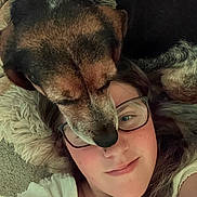 Ruby is registered to the contest to win money with this photo: dog, person, face, glasses, lying_down, carpet, fur, close_up, affection, smile, nose_ring, indoor, casual_clothing, brown_fur, black_fur, white_clothing, cozy, resting, pet, human