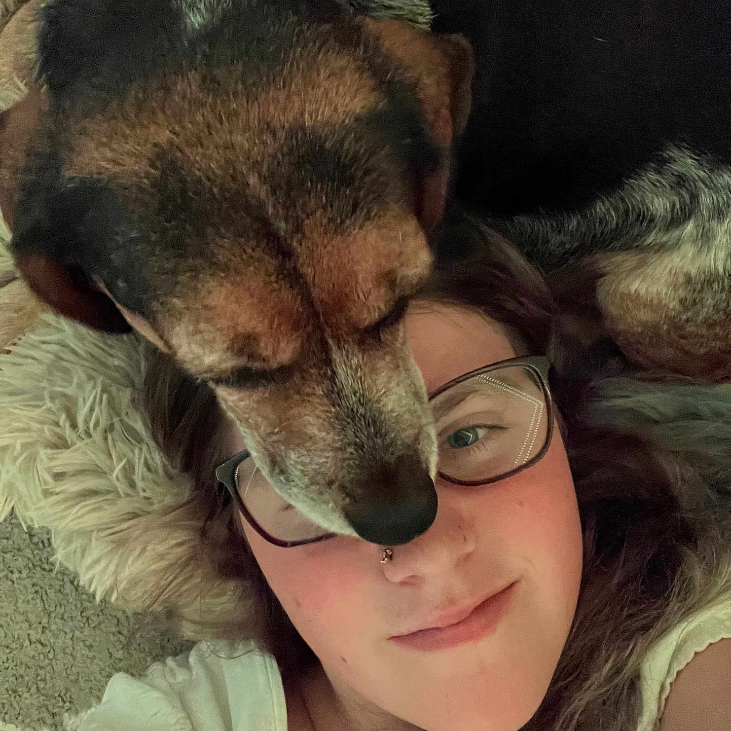 Ruby is registered to the contest to win money with this photo: dog, person, face, glasses, lying_down, carpet, fur, close_up, affection, smile, nose_ring, indoor, casual_clothing, brown_fur, black_fur, white_clothing, cozy, resting, pet, human