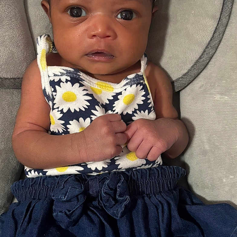 Treazure is registered to the contest to win money with this photo: baby, blue_skirt, bow, child, clothing, cushion, cute, daisy, dress, eyes, face, hands, headwear, indoors, infant, pattern, portrait, seat, sitting, skin