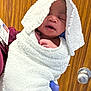 newborn, baby, towel, wrapped, sleeping, hand, glove, person, indoor, door, wood, white, purple_glove, infant, cute, cozy, portrait, skin, face, holding
