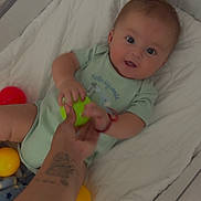 Izael joined the competition — help win amazing prizes! baby, crib, colorful_balls, hand, tattoo, green_ball, red_ball, yellow_ball, blanket, onesie, infant, smiling, child, indoor, playtime, cute, person, baby_toys, soft_bedding, happy