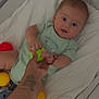 baby, crib, colorful_balls, hand, tattoo, green_ball, red_ball, yellow_ball, blanket, onesie, infant, smiling, child, indoor, playtime, cute, person, baby_toys, soft_bedding, happy