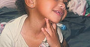 Cimani joined the competition — help win amazing prizes! baby_clothes, bed, blanket, bracelet, child, curly_hair, cute, earrings, foot, hand, happy, indoor, pacifier, person, pillow, portrait, red_bow, skin, smile, toddler