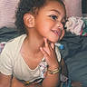 toddler, child, smile, curly_hair, red_bow, bed, pillow, blanket, bracelet, earrings, pacifier, indoor, portrait, cute, happy, person, baby_clothes, skin, hand, foot