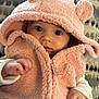 baby, child, pink_jacket, hood, bear_ears, cute, infant, face, eyes, hand, fleece, warm_clothing, cushion, pattern, soft_texture, indoor, portrait, looking_at_camera, closeup, adorable