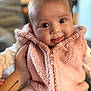 Kennedi is registered to the contest to win money with this photo: baby, child, face, eyes, tongue, pink_vest, striped_pants, hand, tattoo, indoor, portrait, smile, cute, fluffy_clothing, cozy, infant, person, soft_focus, warm_colors, closeup