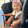 Kennedi is registered to the contest to win money with this photo: baby, child, infant, smiling, happy, portrait, car_seat, vehicle, pink_bow, headband, dress, bib, bare_feet, sitting, indoors, daylight, window, gummy_smile, safety_harness, close_up