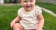Kennedi is registered to the contest to win money with this photo: baby, child, infant, smiling, laughing, sitting, outdoor, grass, backyard, garden, floral_clothing, romper, barefoot, portrait, close_up, sunlight, sky, blurred_background, happy, lawn