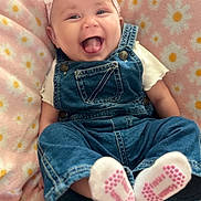 Kennedi is registered to the contest to win money with this photo: baby, denim_overalls, headband, pink_bow, smiling, tongue_out, blanket, daisy_pattern, soft_texture, cute, child, infant, happy, sitting, footwear, socks, clothing, portrait, indoor, person