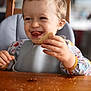 toddler, child, high_chair, food, crumbs, table, smile, happy, eating, hand, face, tongue, clothing, indoor, wooden_table, person, cute, messy, meal_time, baby