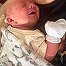 Everett is registered to the contest to win money with this photo: newborn, baby, infant, sleeping, peaceful, face, portrait, close_up, blanket, swaddled, mitten, clothing, adult, holding, indoors, cozy, soft, relaxed, family, cute