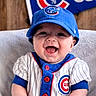 baby, child, smiling, baseball_cap, sportswear, cubs_logo, blue, white, pinstripes, infant, portrait, happy, team_spirit, sitting, clothing, hat, background, flag, cute, person