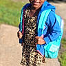 Taelyn is registered to the contest to win money with this photo: child, girl, smiling, blue_hoodie, leopard_print, dress, backpack, sidewalk, outdoor, shoes, sunlight, happy, pose, young, casual_clothing, street, daytime, grass, vehicle, portrait