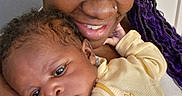 Amari joined the competition — help win amazing prizes! woman, baby, child, smile, holding, indoor, closeup, portrait, face, eyelashes, hair, clothing, baby_bottle, yellow, cheese_graphic, skin, love, family, tender, cuddling