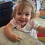 Magnolia is registered to the contest to win money with this photo: toddler, child, smiling, baby, indoor, living_room, couch, cushion, dress, hair_bow, person, happy, face, eyes, hand, furniture, home, toy, carpet, skin
