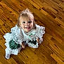 toddler, child, dress, frilly, white, green, tongue_out, smiling, happy, floor, wooden_floor, sitting, cute, indoors, portrait, person, clothing, young_child, playful, baby