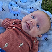 River joined the competition — help win amazing prizes! baby, smiling, blue_eyes, blanket, sheep_pattern, grass, outdoor, cute, infant, cactus_print, clothing, lying_down, happy, child, portrait, soft_texture, nature, toddler, face, young_child