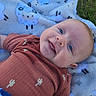 baby, smiling, blue_eyes, blanket, sheep_pattern, grass, outdoor, cute, infant, cactus_print, clothing, lying_down, happy, child, portrait, soft_texture, nature, toddler, face, young_child
