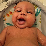 Mateo joined the competition — help win amazing prizes! baby, infant, smiling, wet_skin, bathtub, towel, lying_down, happy, chubby_cheeks, close_up, skin, face, water_droplets, bath_time, cute, person, indoors, colorful_background, baby_bath, newborn