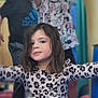 child, girl, leopard_print, dress, smile, portrait, indoor, playful, children, person, long_hair, happy, casual_clothing, colorful_background, blurred_background, necklace, fun, friends, arms_outstretched, young