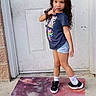 Serenity is registered to the contest to win money with this photo: child, girl, posing, door, mat, space_theme, tshirt, shorts, socks, shoes, outdoor, concrete, confident, curly_hair, playful, casual_clothing, standing, front_yard, expression, youth