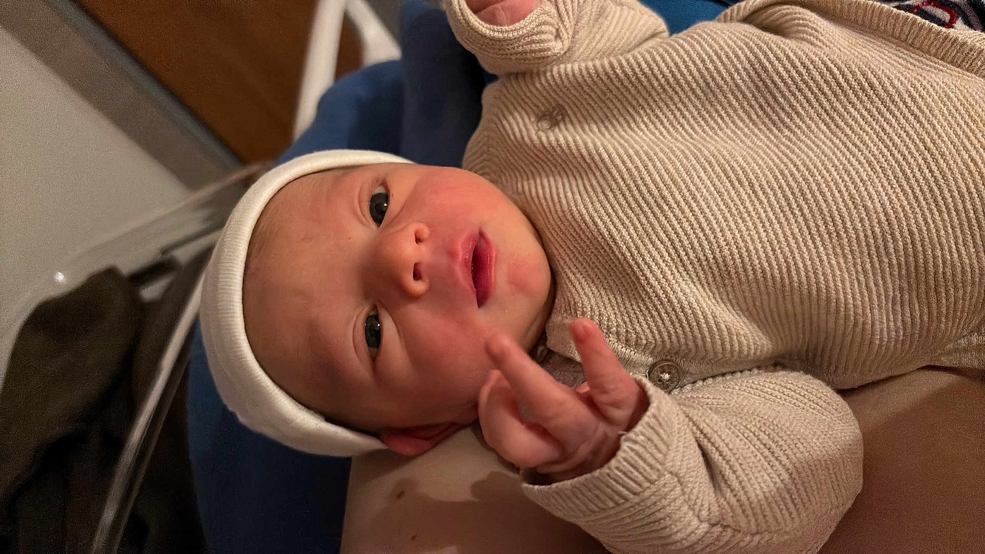 Harry participe au concours pour gagner de l'argent avec cette photo : baby, newborn, infant, hat, sweater, clothing, face, hand, fingers, expression, portrait, indoor, person, skin, headwear, cute, young_child, lying_down, closeup, baby_gesture