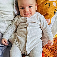 Harry a rejoint le concours — aidez-le/la à gagner de superbes lots ! baby, bed, child, comfort, cozy, crocheted_blanket, cute, expression, face, happy, indoor, infant, lying_down, onesie, person, pillow, sleepwear, smile, soft, young