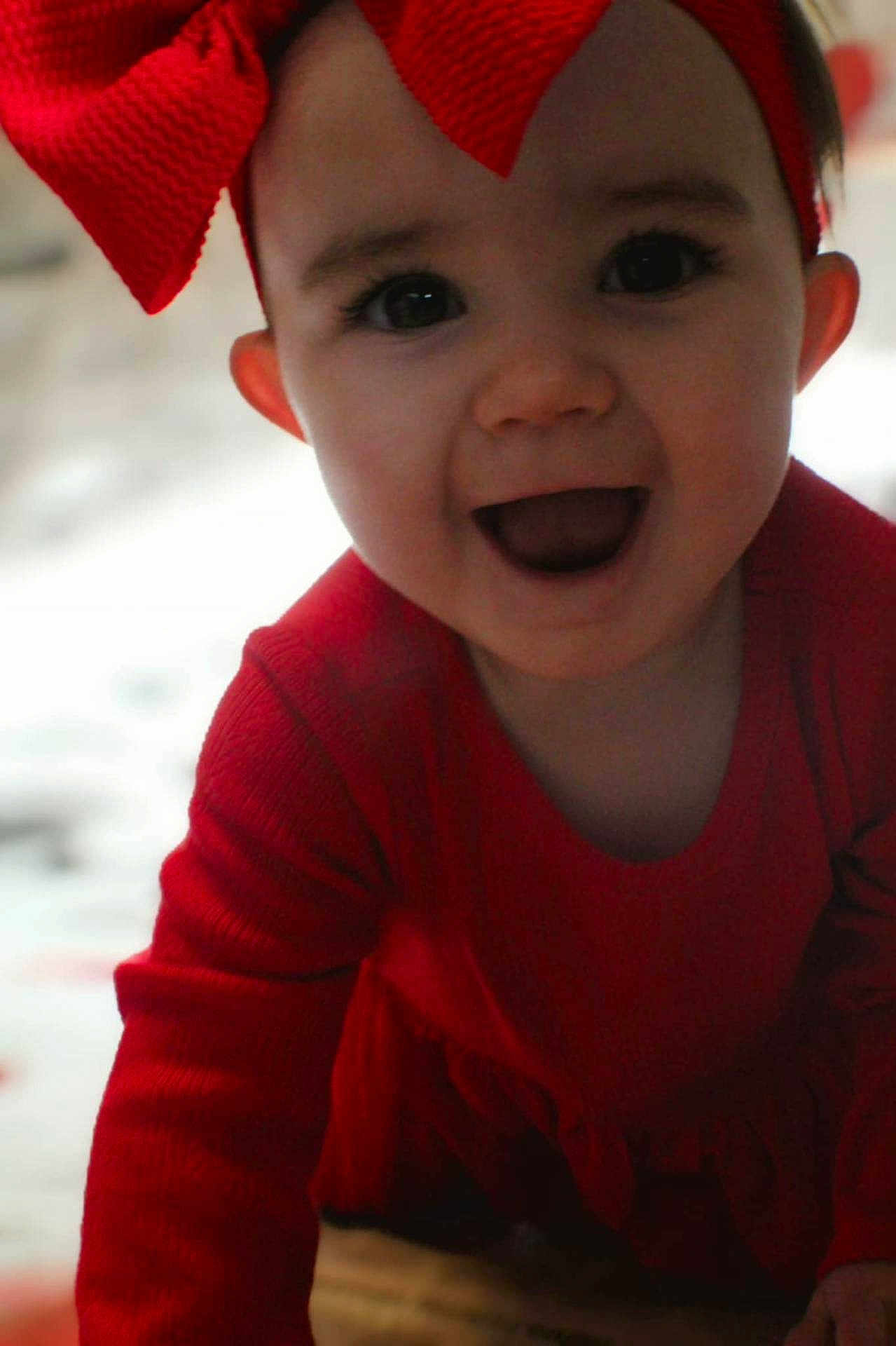 Piper Yost joined the competition — help win amazing prizes! baby, child, red_clothing, red_bow, smiling, happy, face, cute, infant, portrait, indoors, crawling, headwear, long_sleeve, human, closeup, young_child, expression, bright, cheerful