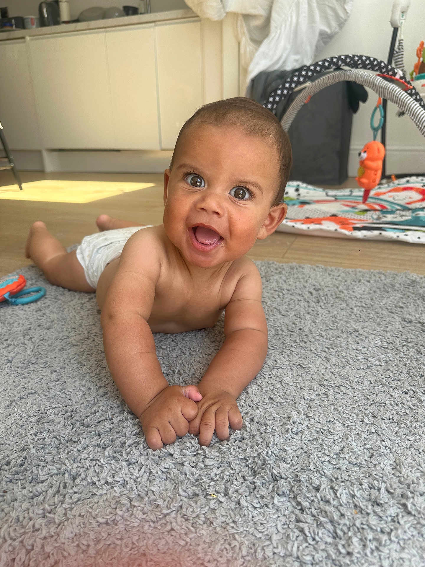 Elyas is registered to the contest to win money with this photo: baby, child, smiling, happy, toddler, indoor, carpet, toy, playmat, floor, diaper, person, cute, expression, home, infant, skin, hands, face, eyes